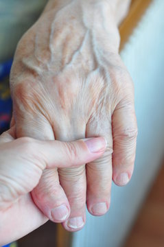 a young and senior hands holding each other