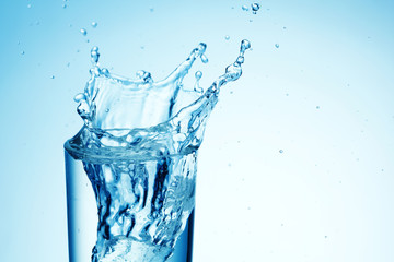 Ice cubes splashing into glass of water