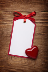address card with bow and heart on old wooden background.