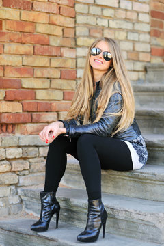 Smiling young girl sitting on the stairs in sunglasses