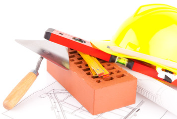 brick, yellow hard hat, tools and construction plans
