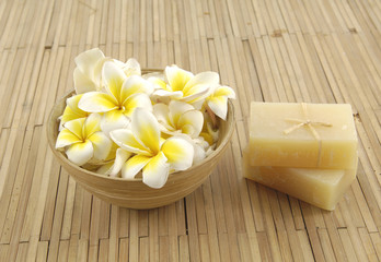 Fototapeta na wymiar frangipani flower in bowl with natural handmade soap onmat