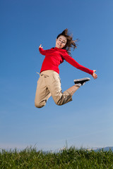 Girl jumping, running against blue sky