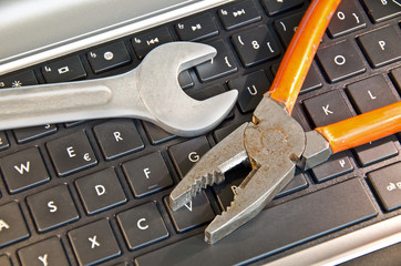 Zange und Schraubenschlüssel liegen auf Computer Tastatur