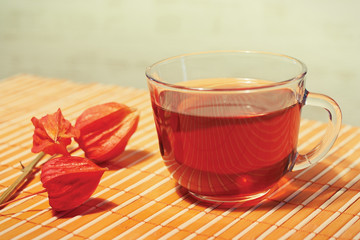 Cup of tea and physalis on a bamboo table cloth still life