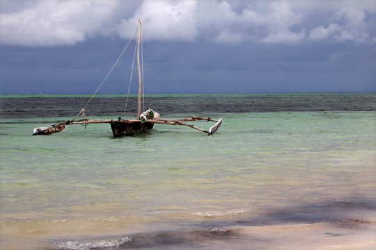 Traditional dhow boat anchored in shallow sea on Zanzibar.