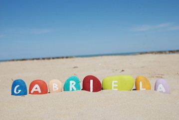 Obraz premium gabriela, female name on colourful pebbles on the sand