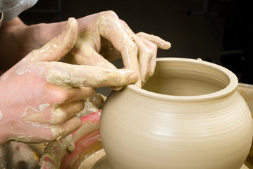 hands of a potter, creating an earthen jar of white clay