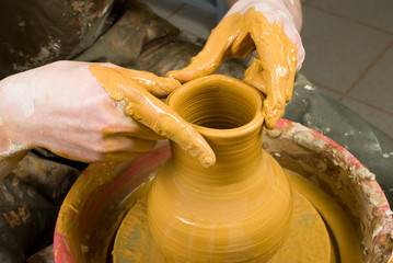 hands of a potter, creating an earthen jar of white clay