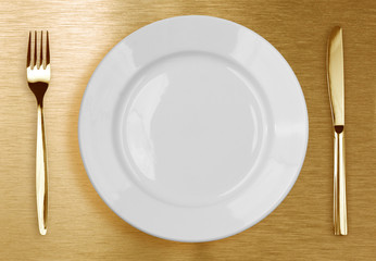 Golden knife, fork and white plate