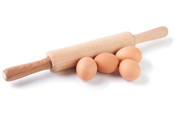 Brown eggs and rolling pin, isolated on white background