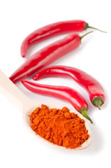Chili powder in a wooden spoon and chili peppers