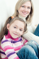 Cute little girl sitting on the floor at home with her mother