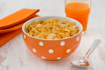 cornflakes in the bowl with spoon and juice