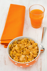 cornflakes in the bowl with spoon and juice