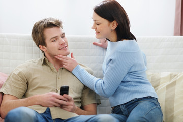 Young woman trying to distract boyfriend from mobile phone - obrazy, fototapety, plakaty
