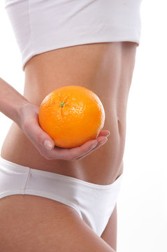 Sexy body of a young woman holding a fresh orange