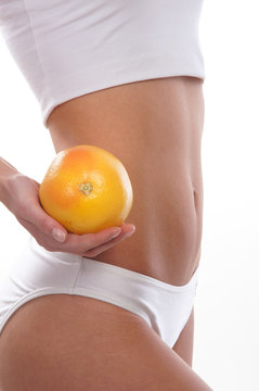 Sexy body of a young woman holding a fresh grapefruit