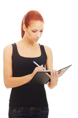 A young redhead Caucasian woman writing to a book