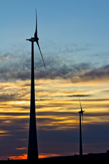 two wind turbines of the wind farm at sunset