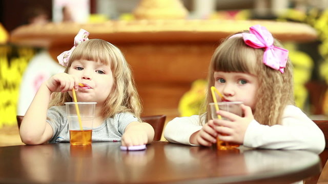 Two girls drinking juice and looking at camera