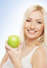 A young blond woman holding a fresh green apple