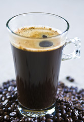 Czarna kawa w szklance i ziarenka