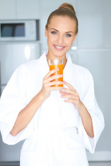 Fototapeta premium Woman in bath robe drinking orange juice