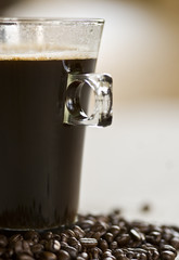 Czarna kawa w szklance i ziarenka