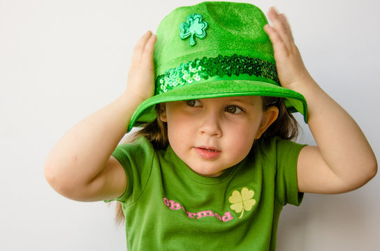 Pretty little girl tries on a fancy hat for St. Patrick's Day