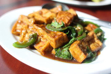 Plate of tofu with basil and chili pepper sauce.
