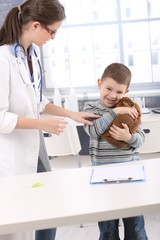 Fototapeta premium Boy cuddling with pet rabbit at vet office