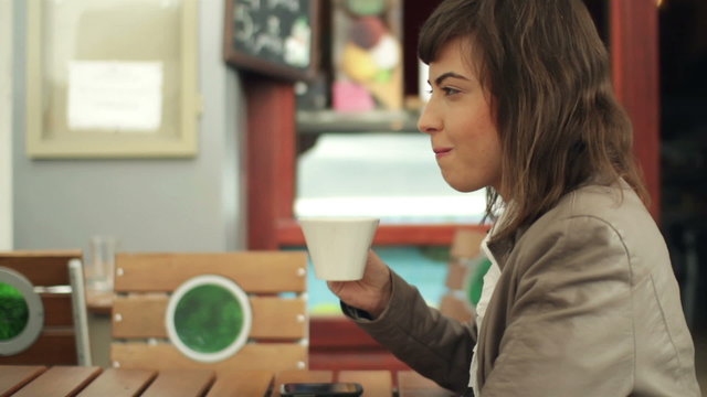 Young happy woman drinking coffee in cafe, steadicam shot