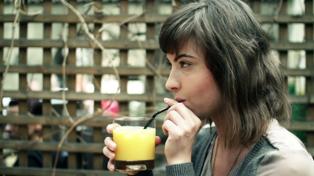 Happy woman drinking juice in outdoor bar, steadicam shot