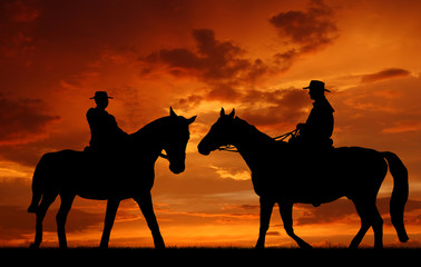 Silhouette cowboys with horses in the sunset