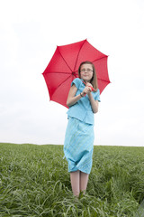 girl with ed umbrella in meadow