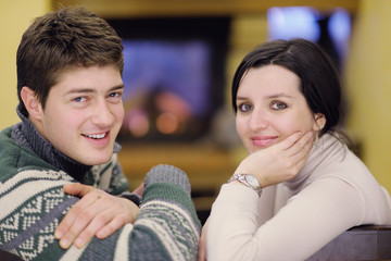 Fototapeta na wymiar Young romantic couple relaxing in front of fireplace at home