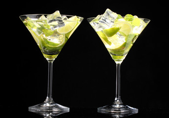 glasses of cocktails with lime and mint on black background