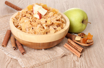 tasty cornflakes in bowl with dried fruits, glass of milk and