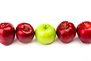 Green apple among red apples isolated on a white