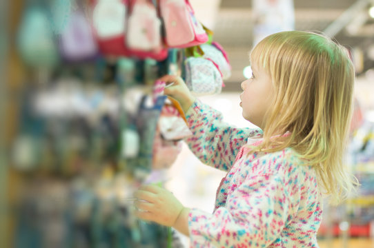 Adorable baby with toys on shelves in mall