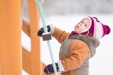 Adorable baby climb on rope ladder on playground in park