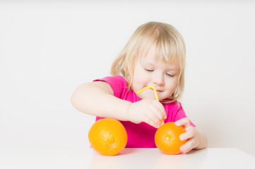 Fototapeta na wymiar Adorable baby suck juice from orange with straw
