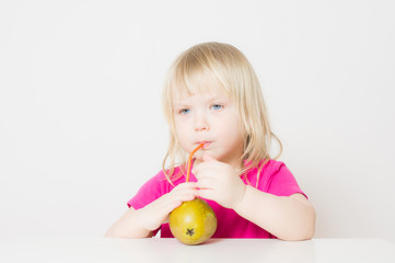 Fototapeta premium Adorable baby suck juice from pear with straw