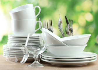 Clean dishes on wooden table on green background