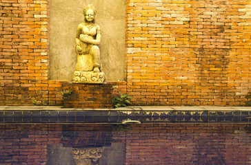 asian sculpture at brick wall