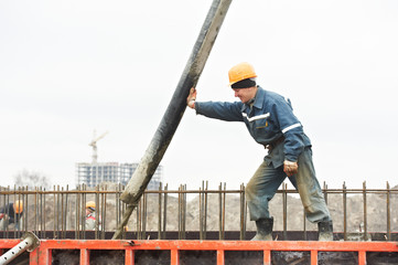 builder worker pouring concrete into form