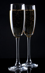 two glasses of champagne on black background