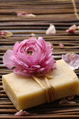Obraz na płótnie Canvas ranunculus flower with petals and handmade soap on mat
