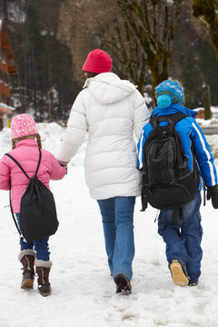 Mother Walking Two Children To School Along Snowy Street In Ski